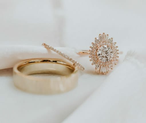 Three luxury gold rings, two with diamonds and one with a solid band, all laid out on white cloth.