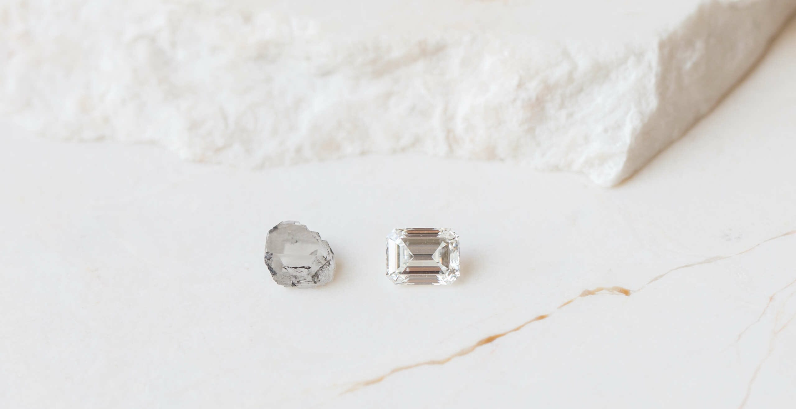 Two diamonds of different size on a while marble table. showing different carat weights.