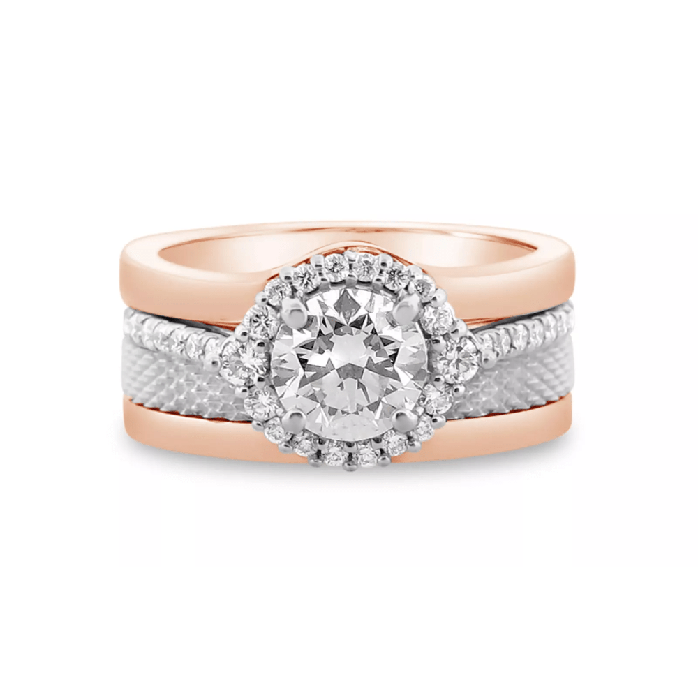A bespoke rose gold ring with a thicker band and a smaller band in the middle with smaller diamonds around it leading up to a round cut center stone diamond.