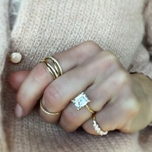 An emerald cut diamond in someones engagement ring that is being shown off on her hand.