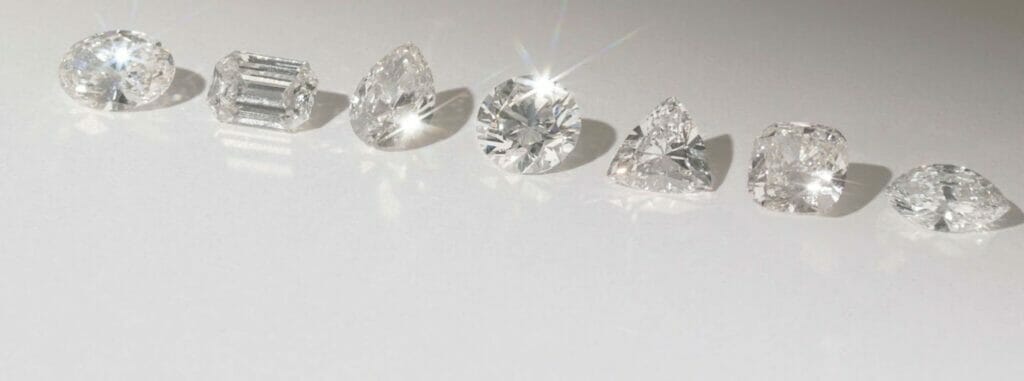 Multiple diamond shapes including - pear, emerald, round, heart cut diamonds, sitting on a white background