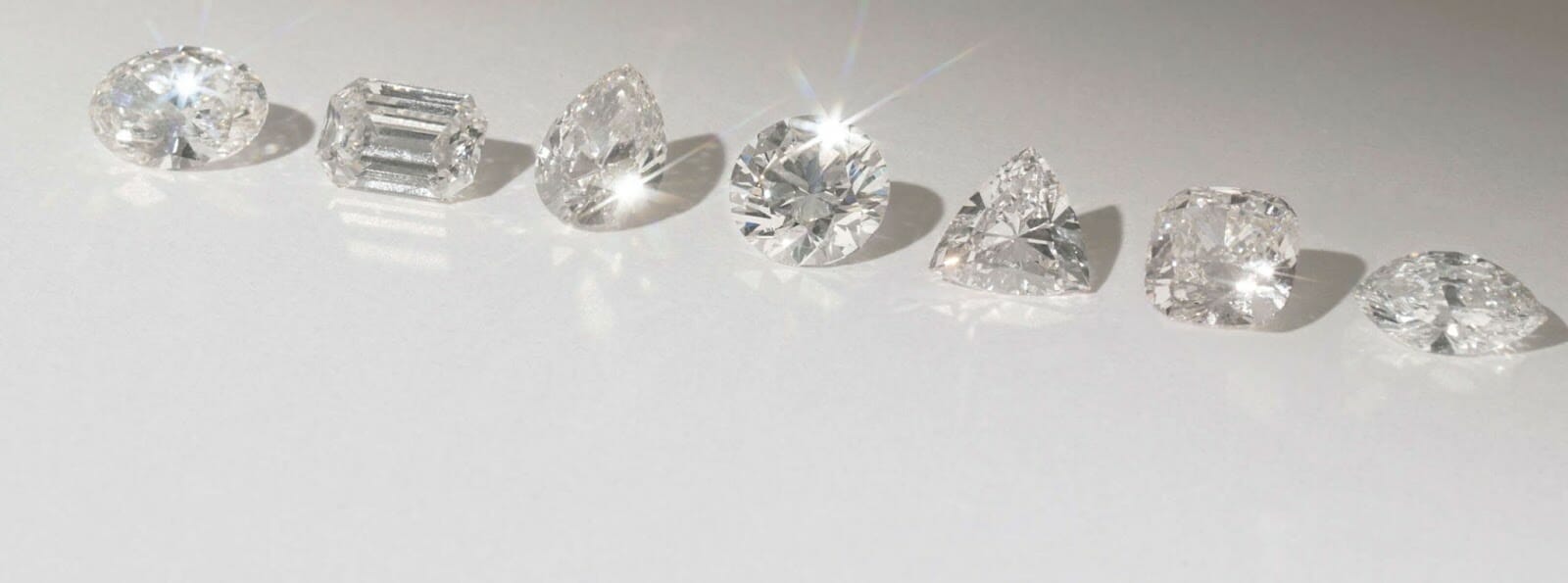 Multiple diamond shapes including - pear, emerald, round, heart cut diamonds, sitting on a white background
