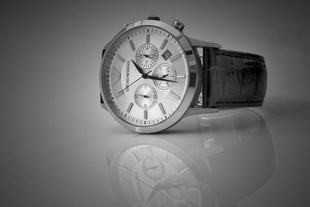Luxury switch watch with leather band, in black and white on a glossy surface