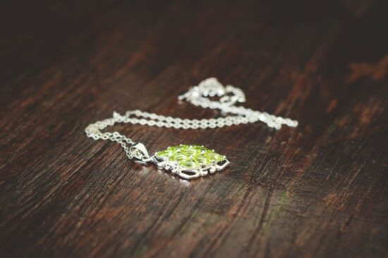 Vintage white gold necklace with a large light green pendant on a wood table